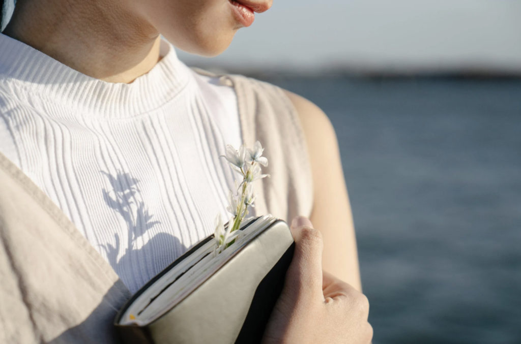 girl holding a journal and flower