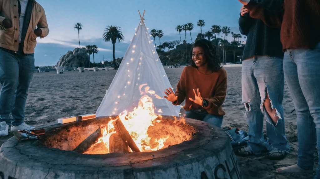 girl sitting next to a bonfire