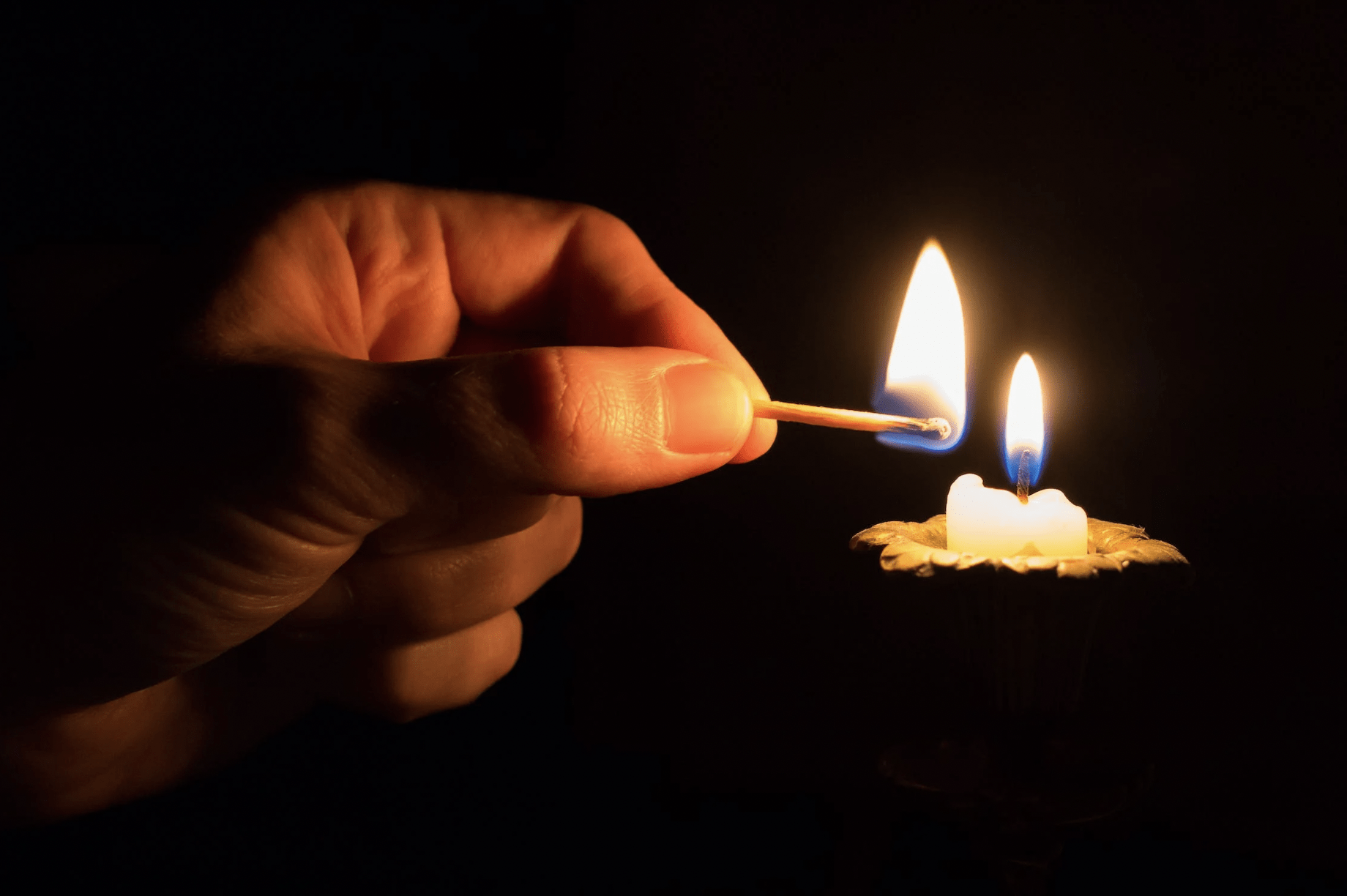 hand lighting a candle