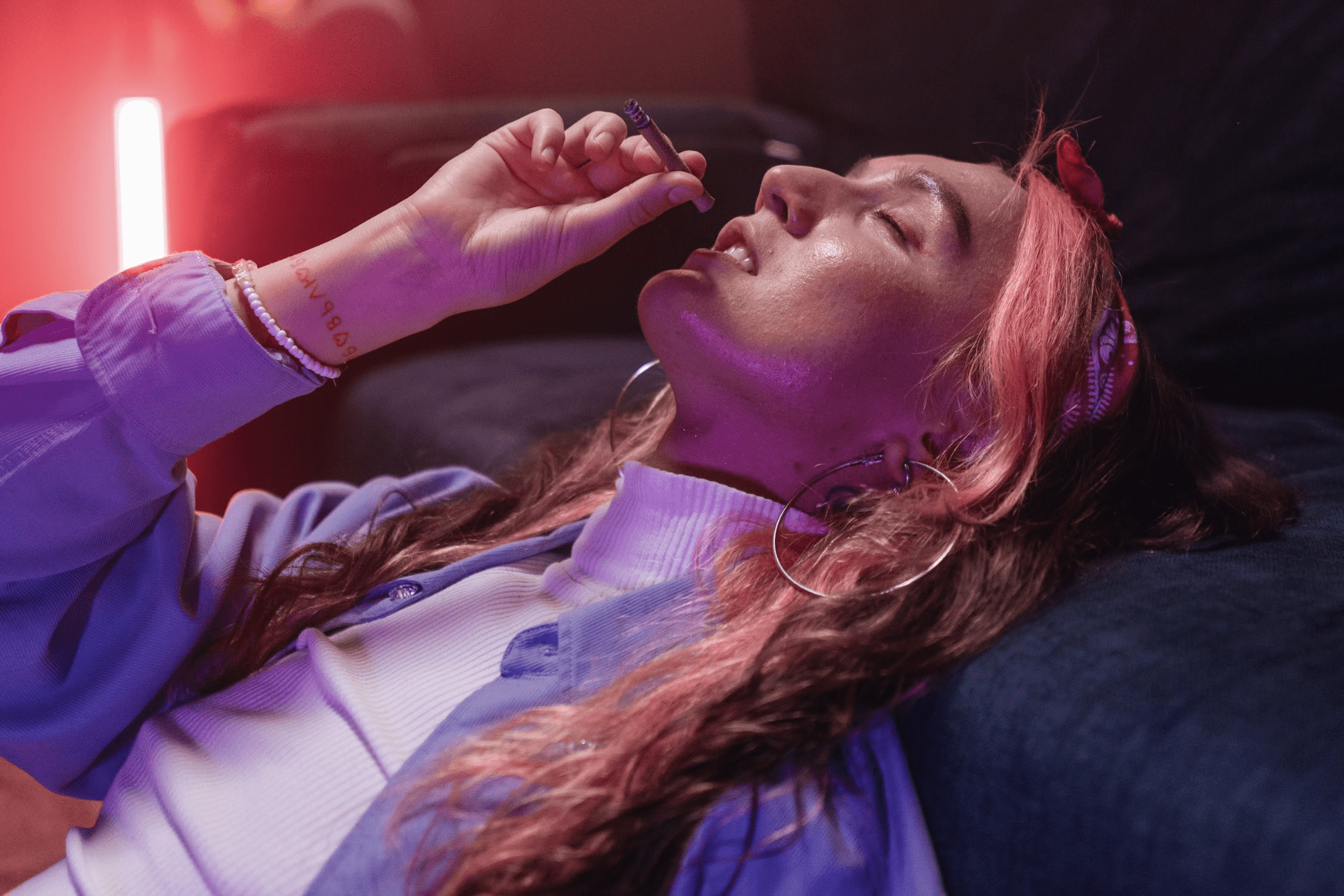 woman smoking with her eyes closed and leaning back on a couch 