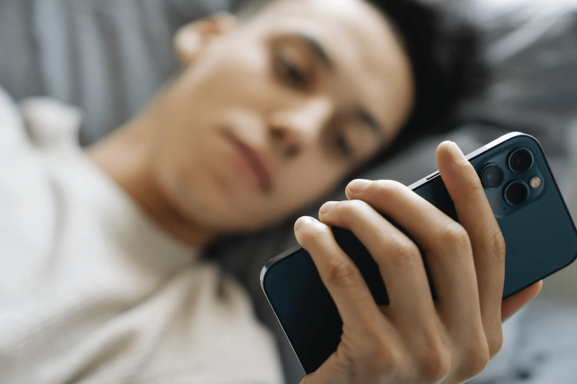 guy browsing mobile phone in bed