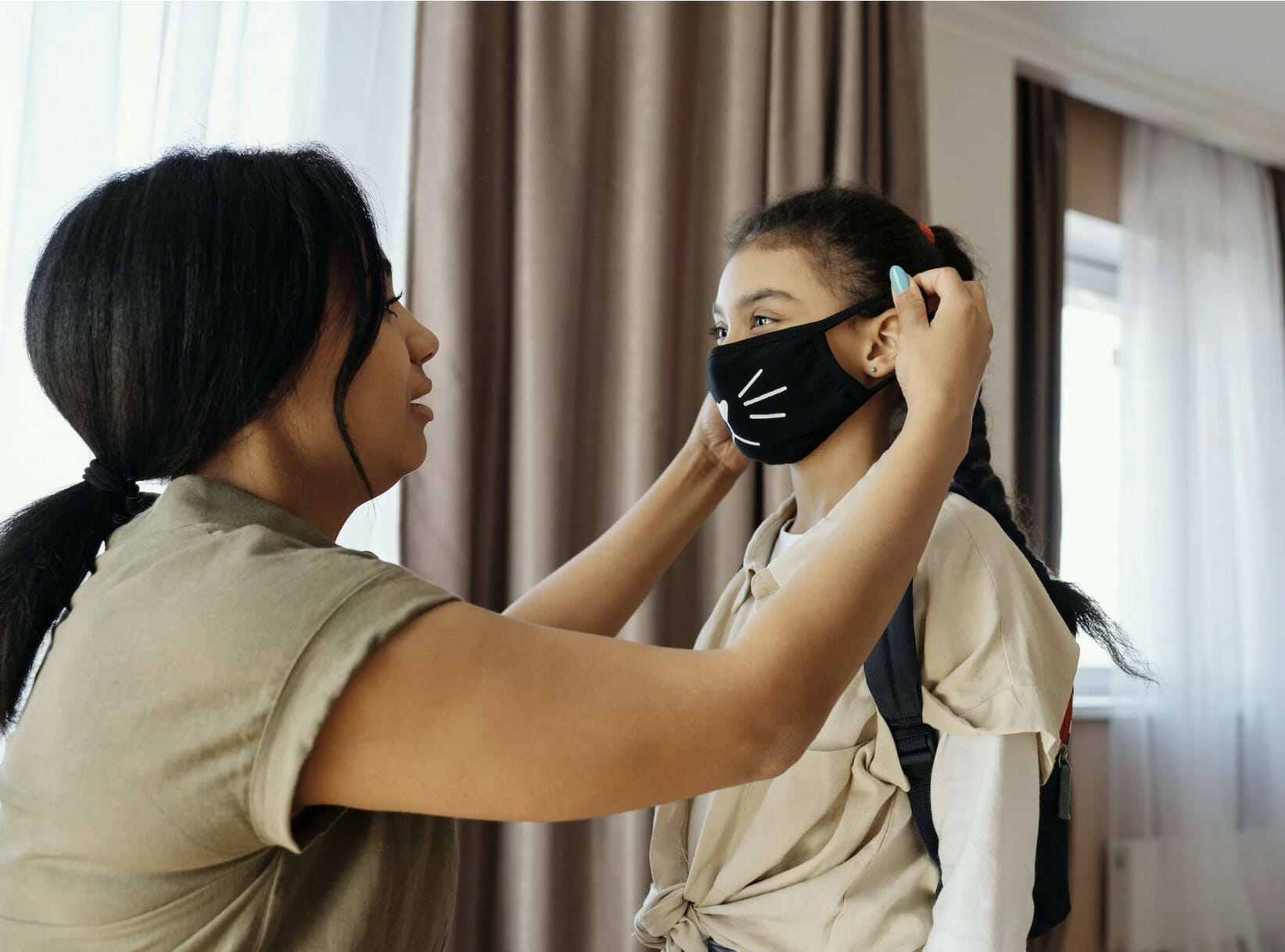 mother putting face mask on her daughter