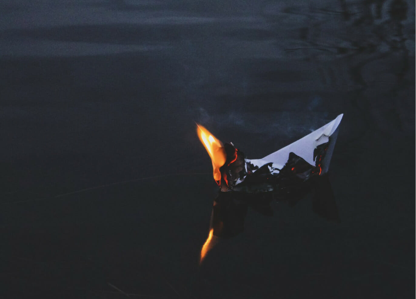 paper boat burning while floating on water