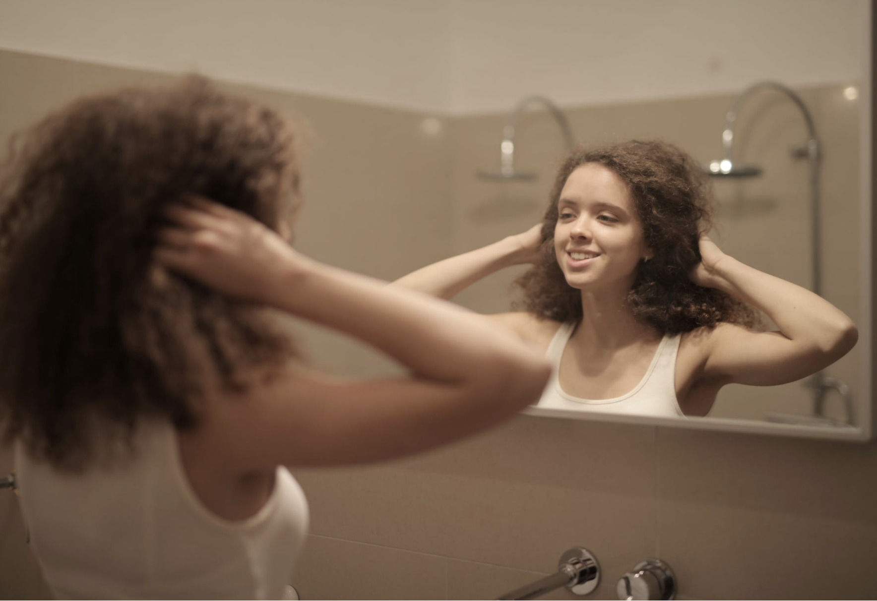 woman smiling at her reflection in the mirror
