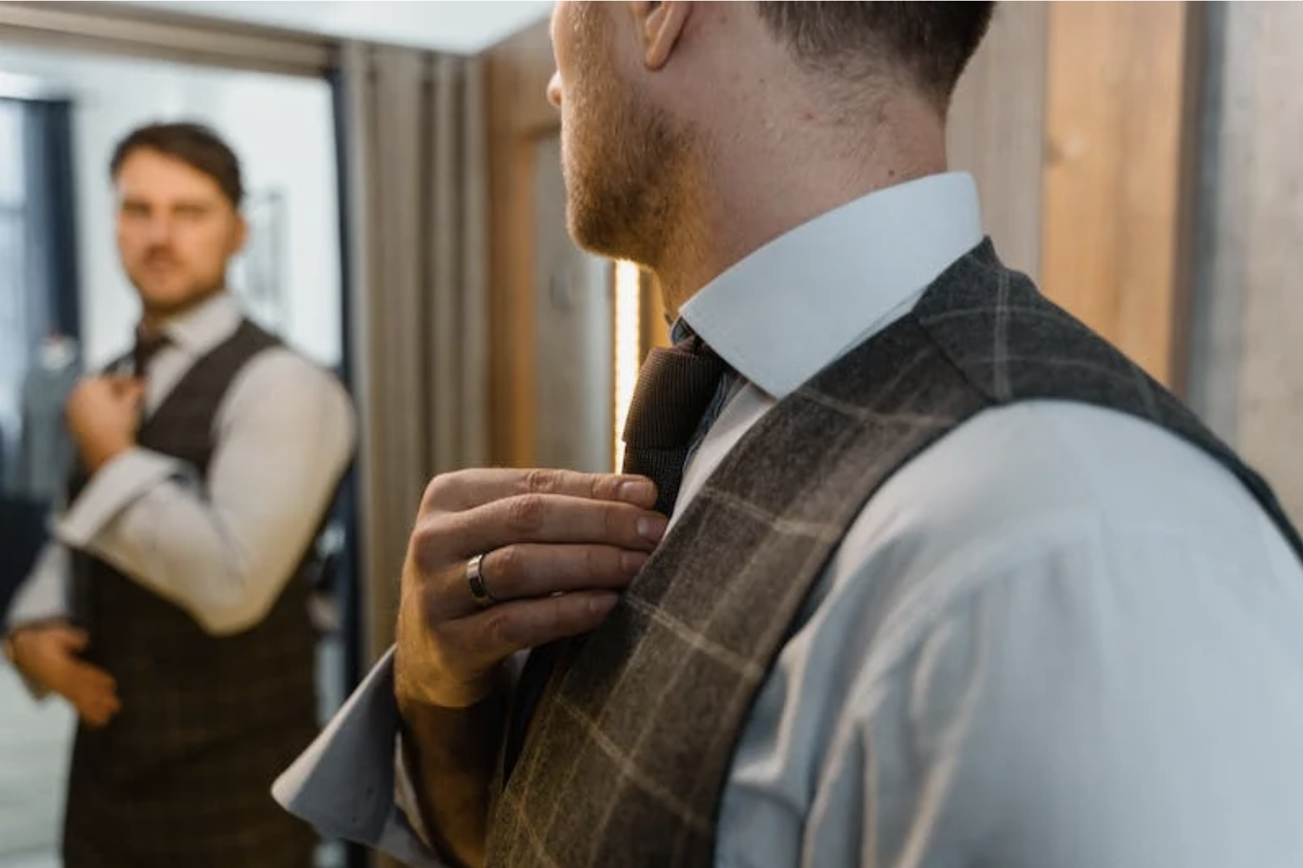 man in a suit looking at his mirror reflection